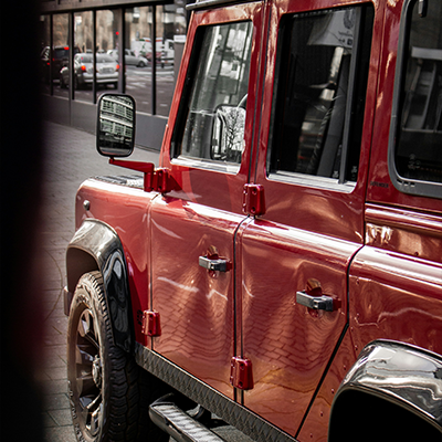 Red Land Rover Defender parked in an urban setting serviced by Bentley Auto Centre